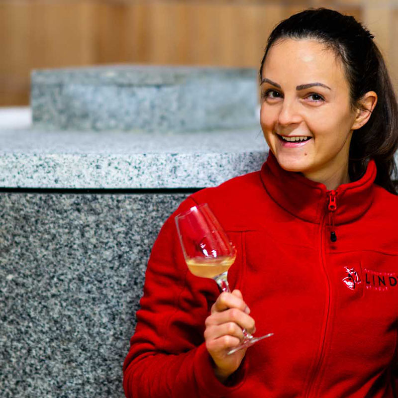 Elena Lind mit ihrem Granitsteinfass und einem RIESLING GRANIT Sélection Noir im Weinglas.