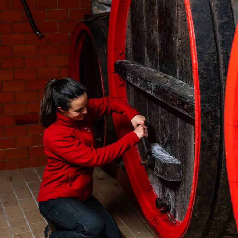 Elena Lind bricht (öffnet) die Tür von einem über 140 Jahre altes Rotweinholzfass.